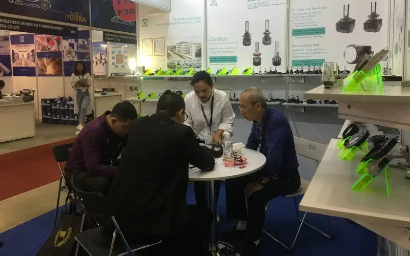NVEL sales team showcasing LED headlight kits and Bi-LED projector lenses at automotive exhibition booth