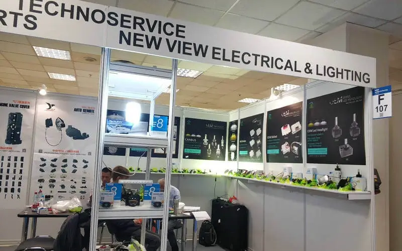 NVEL sales team showcasing LED headlight kits and Bi-LED projector lenses at automotive exhibition booth